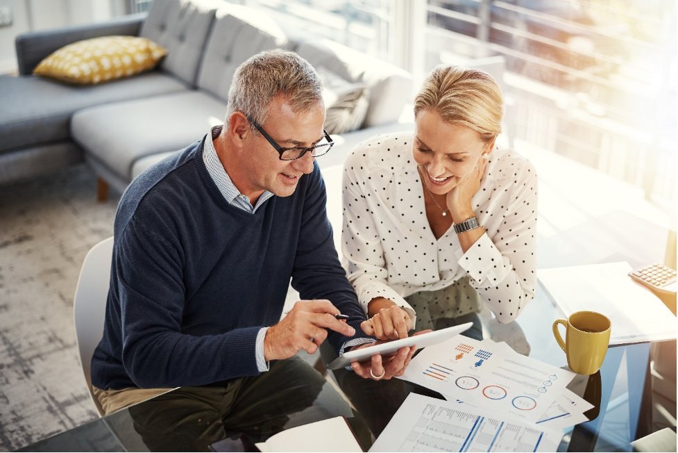 Shot of a mature couple using a digital tablet while going through paperwork at home by tinpixels/istockphoto 